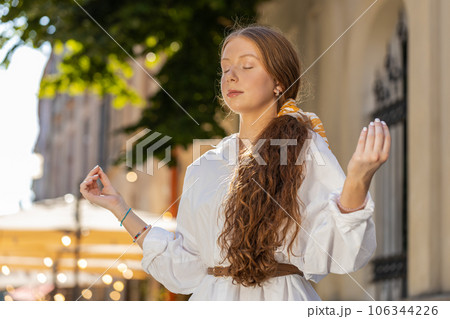 Teenager adult child girl relaxing meditating with eyes closed, peaceful mind outdoors city street 106344226