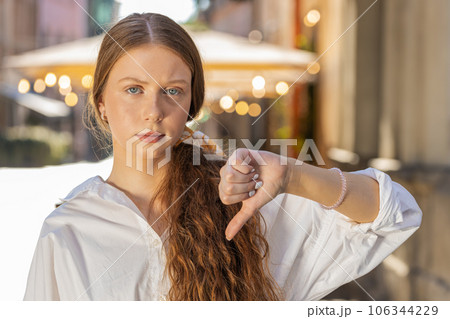 Upset child girl woman showing thumbs down sign, disapproval, dissatisfied bad work, mistake in city 106344229