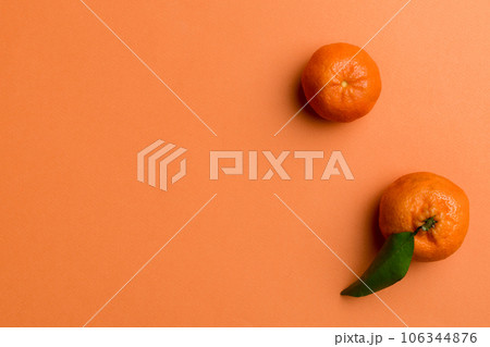 Many fresh ripe mandarin with green leaves on colored background, top view, space for text 106344876