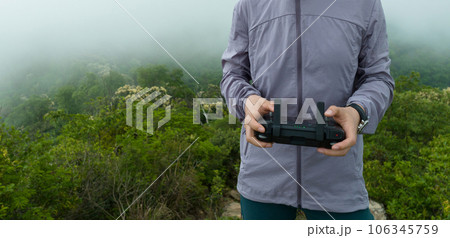 People remote contrlling a flying drone in spring forest People remote contrlling a flying drone in spring forest 106345759