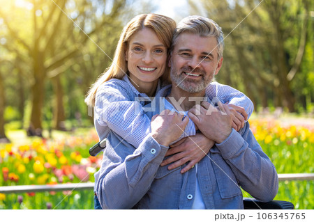 Woman and disabled man in wheelchair walking in park, romantic walking. 106345765