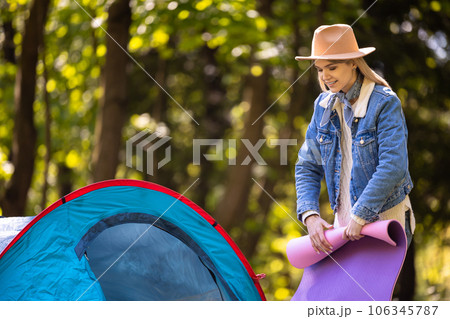Young blonde woman stending near the tent with a mat in hands 106345787