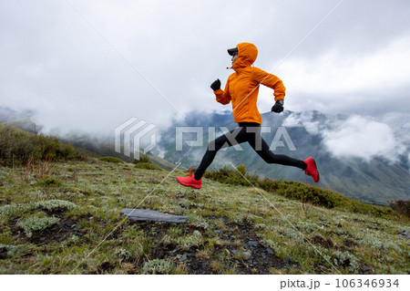 Woman trail runner cross country running at high altitude mountain peak 106346934