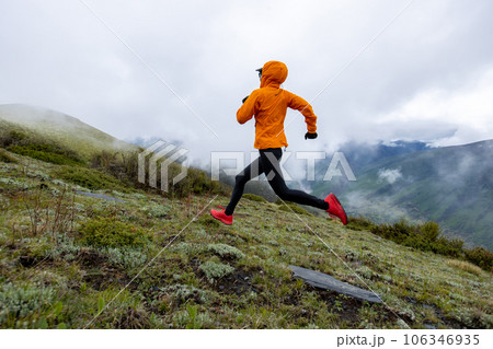 Woman trail runner cross country running at high altitude mountain peak Woman trail runner cross country running at high altitude mountain peak 106346935