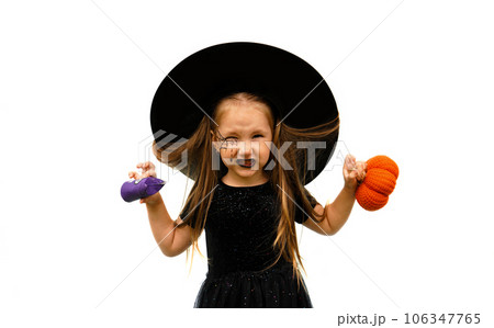Portrait of winsome little witch angry upset girl wearing a wizard hat and dressed in stylish carnival dress, looking at camera posing against white background, Halloween 106347765