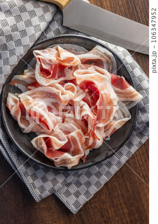 Italian panchetta. Sliced smoked bacon on plate. Top view. Italian panchetta. Sliced smoked bacon on plate. Top view. 106347952