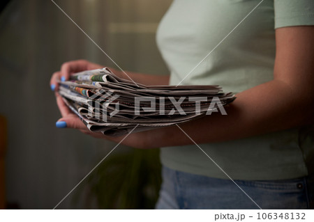 A woman stacks old newspapers in a pile, waste paper collect. A woman stacks old newspapers in a pile, waste paper collect. 106348132