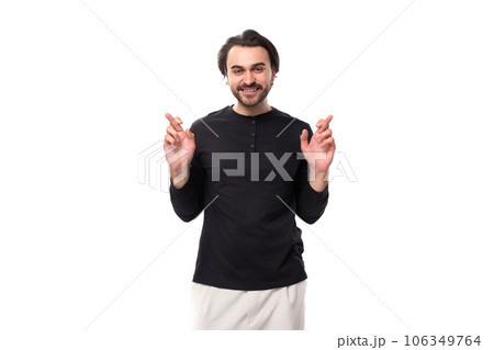 young handsome brunet european masculine man in black sweater crossed his fingers young handsome brunet european masculine man in black sweater crossed his fingers 106349764