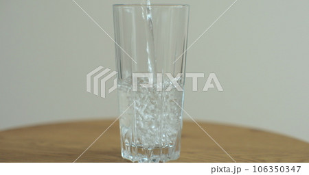 Water pouring to glass. Cold drink pours into a glass. Water in high glass cup. 106350347