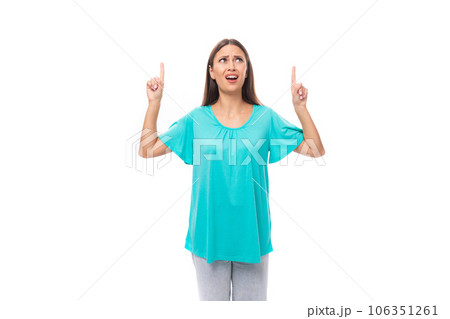 young brunette european lady with straight hair dressed in a blue t-shirt points her hands up at the young brunette european lady with straight hair dressed in a blue t-shirt points her hands up at the 106351261