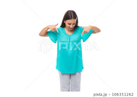 young caucasian female model with black straight hair dressed in a blue t-shirt points with her 106351262