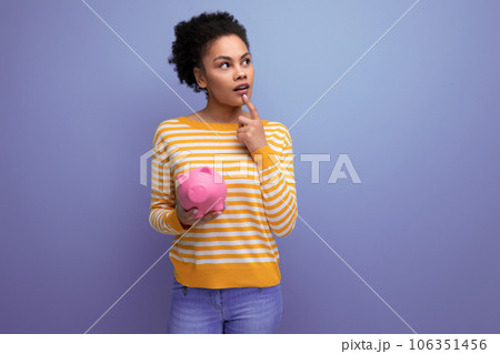 Afro brunette 20s latin young woman decides where to invest the accumulated money from the piggy 106351456