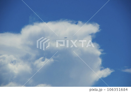 積乱雲の脇を横切る飛行機 106351684