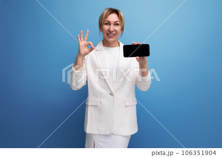 joyful young caucasian blondie lady in elegant jacket holding smartphone with screen mockup joyful young caucasian blondie lady in elegant jacket holding smartphone with screen mockup 106351904