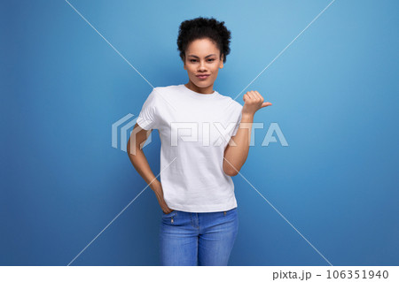 pretty young brunette hispanic woman in a white t-shirt shows with her hands on an empty space for 106351940