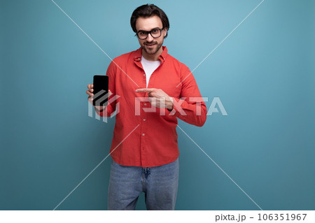 smart handsome young brunette man in glasses and red shirt with smartphone 106351967