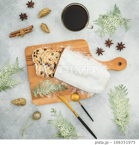 Christmas composition with stollen cake on a wooden board, cutlery and coffee cup on gray table 106351975