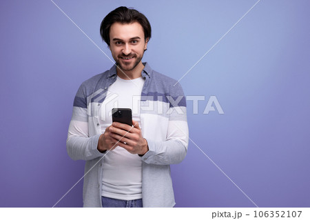 nice brunette guy in casual style communicates using smartphone nice brunette guy in casual style communicates using smartphone 106352107