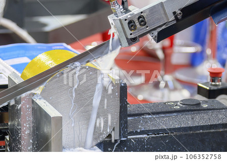 Close up scene the operation of band saw cutting machine cutting the metal shaft parts with coolant method. Close up scene the operation of band saw cutting machine cutting the metal shaft parts with coolant method. 106352758