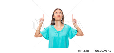 young brunette european lady with straight hair dressed in a blue t-shirt points her hands up at the 106352973