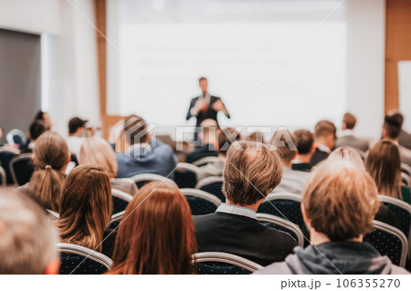 Speaker giving a talk in conference hall at business event. Rear view of unrecognizable people in audience at the conference hall. Business and entrepreneurship concept Speaker giving a talk in conference hall at business event. Rear view of unrecognizable people in audience at the conference hall. Business and entrepreneurship concept 106355270