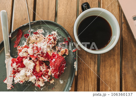 Messed up strawberry cake and cream on the dish with coffee. 106360137