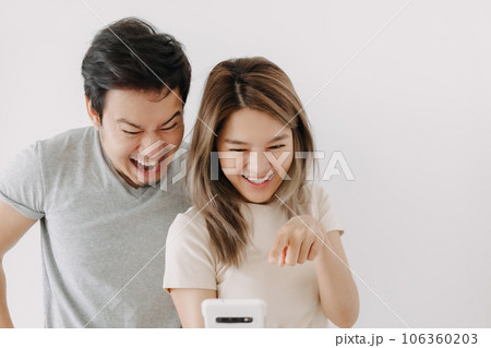 Funny couple lover laugh at the clip in the smartphone isolated on white. Funny couple lover laugh at the clip in the smartphone isolated on white. 106360203