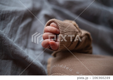 close-up shot. the newborn baby's small hand is folded into a fist on a gray background close-up shot. the newborn baby's small hand is folded into a fist on a gray background 106360289