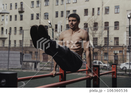 Young man doing parallel bars abdominal exercise. 106360536