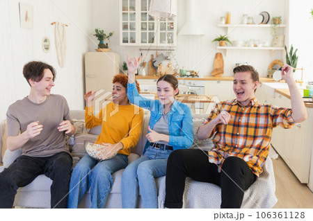 Group of friends watching sport match soccer football game on tv. Happy football fans celebrating victory at home. Friendship sports entertainment concept. Diverse buddies having fun together at home 106361128