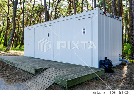 Modern public metal three toilet container with a wooden terrace in a seaside park 106361880