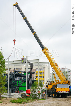 Metal frame mounting around new wood chip biofuel boiler using telescopic boom crane 106361882