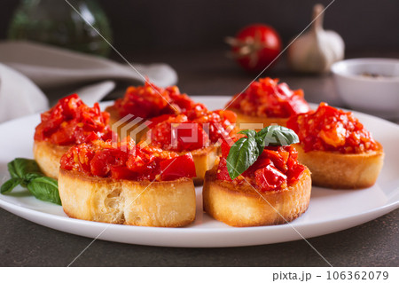 Appetizing crostini on bread with fried tomatoes and garlic on a plate Appetizing crostini on bread with fried tomatoes and garlic on a plate 106362079