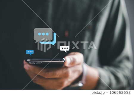 Man smartphone becomes portal for live chat engagement, representing social networking and chatting concepts. Chat box icons highlight interplay of communication and modern technology. 106362658