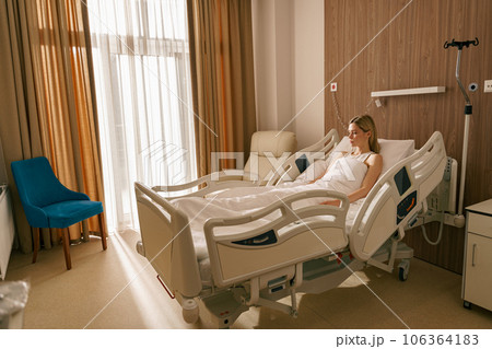 Woman patient lying on bed at modern hospital ward before surgery. Health care and medicine concept Woman patient lying on bed at modern hospital ward before surgery. Health care and medicine concept 106364183