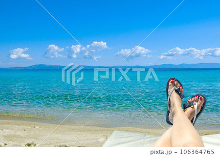 Woman wearing flip-flops laying on the sunbed near the ocean on a beach 106364765