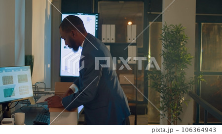Sad businessman getting consoled by colleague during last office nightshift after being fired. Worker holding box filled with desk belongings saying goodbye to coworker after being laid off from job 106364943