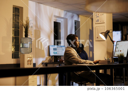 Entrepreneur analyzing company statistics working at financial growth report late at night in startup office. African american manager planning marketing strategy to increase business profit Entrepreneur analyzing company statistics working at financial growth report late at night in startup office. African american manager planning marketing strategy to increase business profit 106365001