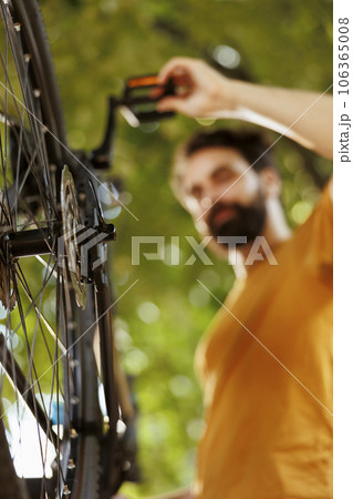 Close-up of bicycle rear derailleur and cogset being serviced and adjusted outside for leisure cycling. Detailed image of bike components being maintained and tested outdoor by sports-loving caucasian 106365008