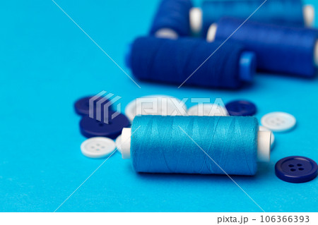Thread spools and buttons on blue abckground Thread spools and buttons on blue abckground 106366393