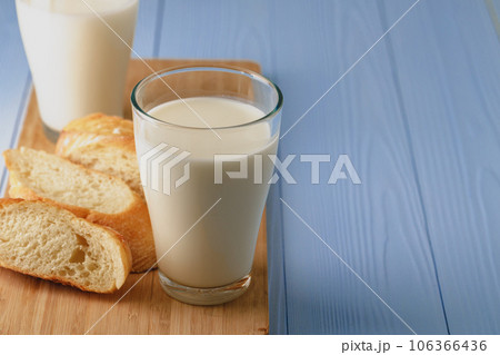 Glass of milk with sliced baguette on wooden board 106366436