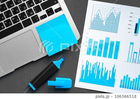 Printed graphs and laptop on dark gray surface 106366518