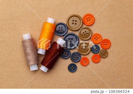 Thread spools and buttons on beige background 106366524