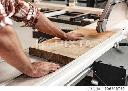 Close-up of carpenter's hands working with wood piece in a workshop 106366713
