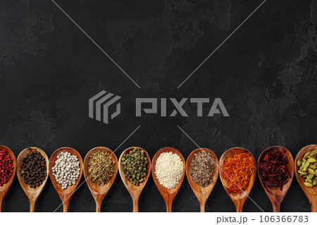Wooden spoons with various spices on black background 106366783