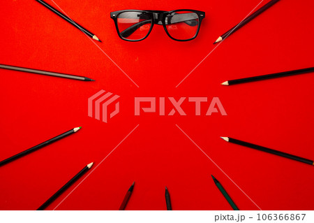 Black pencils and glasses on red background top view Black pencils and glasses on red background top view 106366867