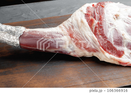 Raw beef leg on brown wooden board 106366916