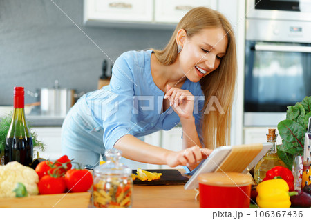 Young beautiful caucasian woman cooking and using her digital tablet in kitchen Young beautiful caucasian woman cooking and using her digital tablet in kitchen 106367436