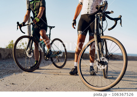 Two male cyclists stand on the road and have a rest 106367526