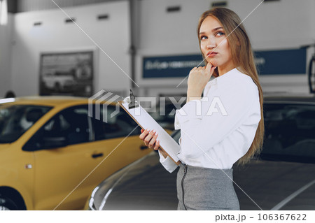 Happy beautiful young woman car dealer in showroom 106367622